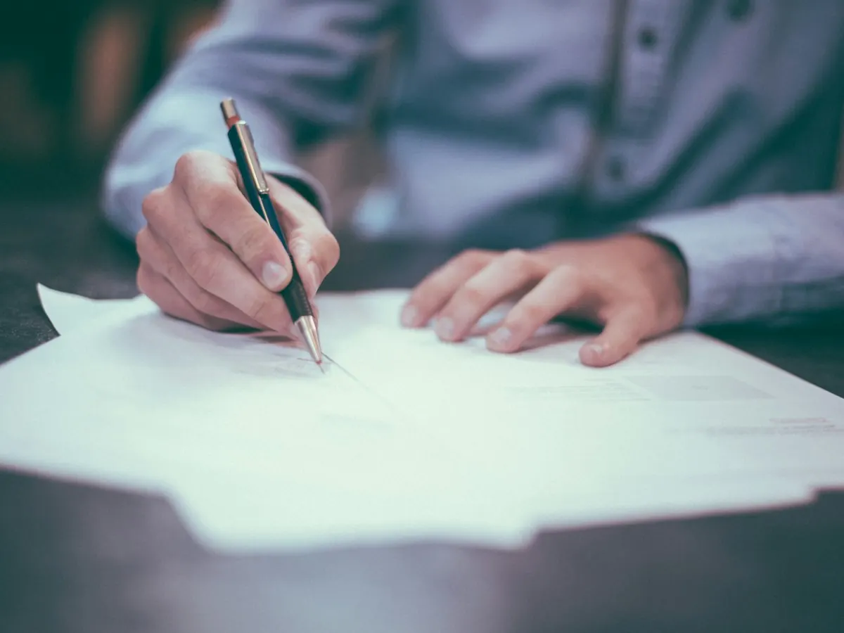 Persona firmando documentos para un cambio de propietario de vehículo