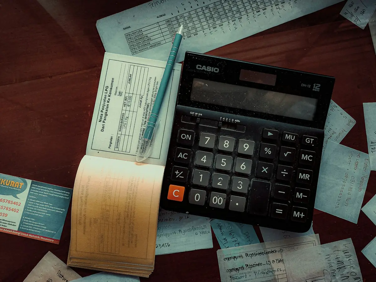 Calculadora, talonarios y recibos sobre una mesa, refacturación de vehículos